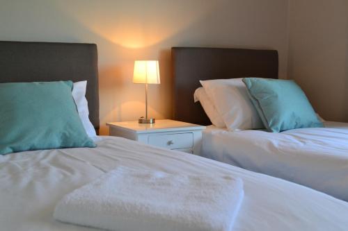 a bedroom with two beds and a lamp on a night stand at Glenrothes Central Apartment in Glenrothes