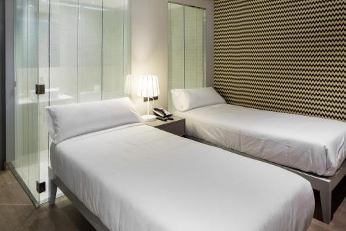a bedroom with two beds and a glass wall at Hotel Atalaia in Santiago de Compostela