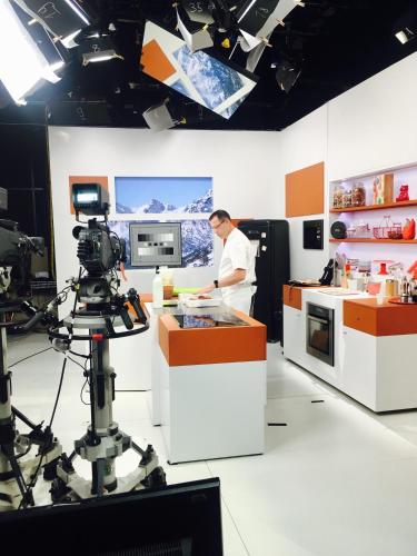 a man preparing food in a kitchen with a camera at Hotel Restaurant L'Europe in Saint-Florent
