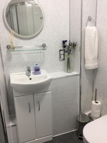 a white bathroom with a sink and a mirror at Connel Court Apartments in Inverness