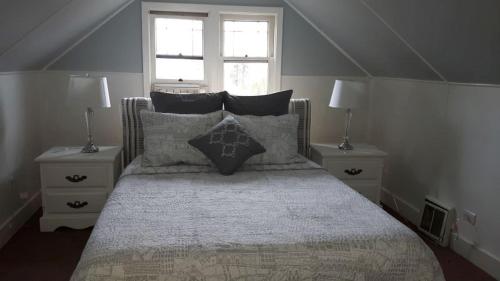 sypialnia z łóżkiem z poduszkami i 2 oknami w obiekcie Campbell Cottage B&B w mieście Nanaimo