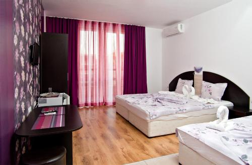 a hotel room with two beds and a table at Cabana Beach Club Complex in Nesebar