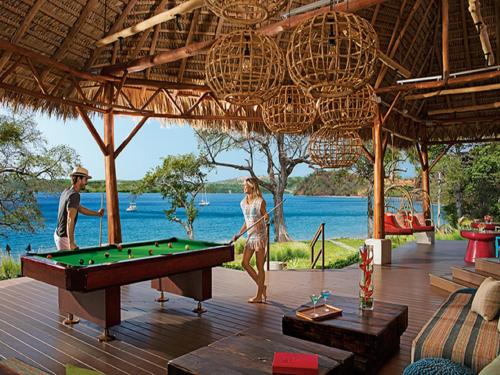 a man and a woman playing pool in a resort at Secrets Papagayo All Inclusive - Adults Only in Culebra