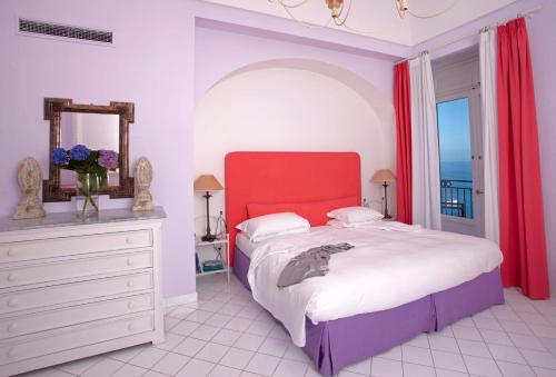 a bedroom with a large bed with a red headboard at Bellevue Syrene in Sorrento
