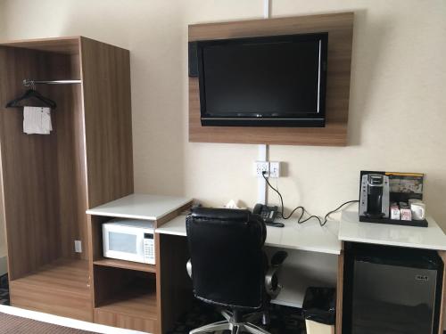 a room with a desk with a computer and a tv at Baymont by Wyndham Medicine Hat in Medicine Hat