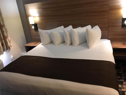 a bed with white pillows in a hotel room at Baymont by Wyndham Medicine Hat in Medicine Hat