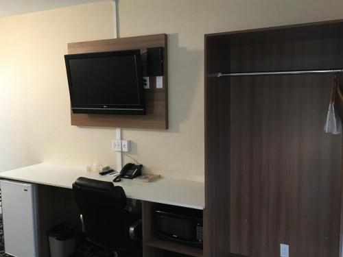 a room with a desk with a tv on the wall at Baymont by Wyndham Medicine Hat in Medicine Hat