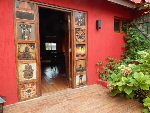 une porte ouverte menant à une maison rouge avec un mur rouge dans l'établissement Villa Olimpia Cabañas, à Villa Gesell