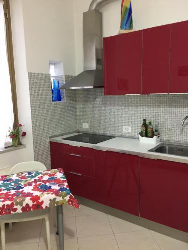 cocina con armarios rojos, fregadero y mesa en Aquila 52, en Roma