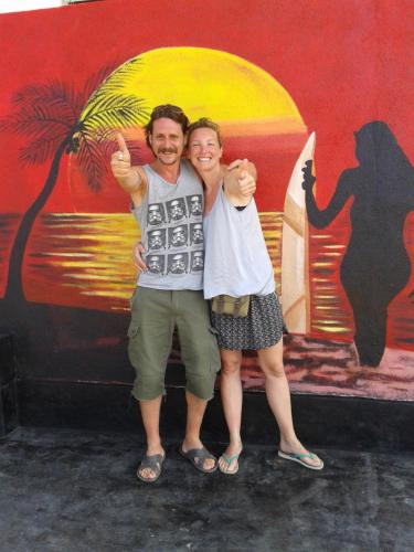 two people posing for a picture in front of a mural at Sunset Surfing Beach Resort in Matara