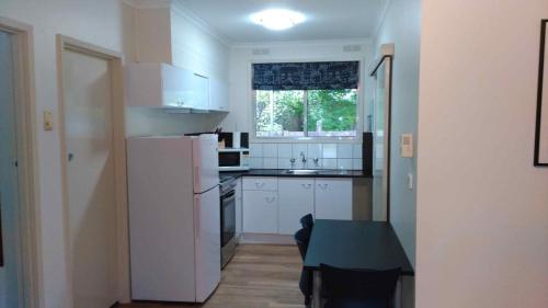 a small kitchen with a white refrigerator and a table at Ageri Holiday Unit in Bright