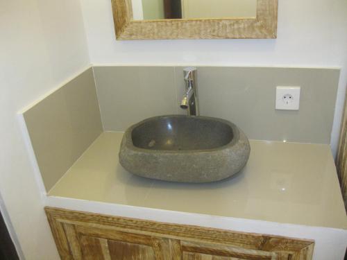a bathroom with a rock sink on a counter at Temuku Guest House in Canggu