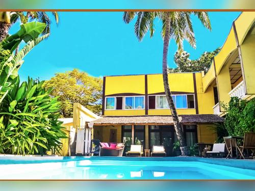 a yellow house with a swimming pool and palm trees at Hôtel Restaurant Coco Lodge Majunga in Mahajanga