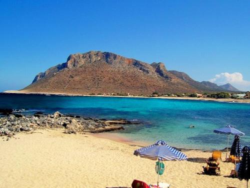 a beach with umbrellas and the ocean and a mountain at Anni House in Stavros in Stavros