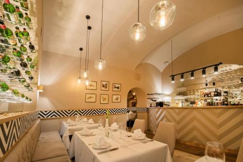 a restaurant with white tables and a bar at Promenáda Romantic Hotel in Karlovy Vary