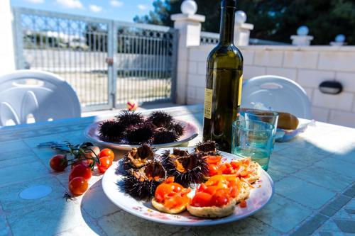 two plates of food on a table with a bottle of wine at Complesso Gardencasa in Torre Suda