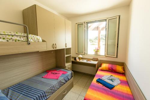 トッレ・スーダにあるComplesso Gardencasaのベッド2台と窓が備わる小さな客室です。