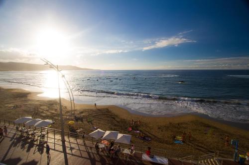 a view of a beach with the sun and the ocean at Living Las Canteras Homes - FRONT-LINE BEACH in Las Palmas de Gran Canaria
