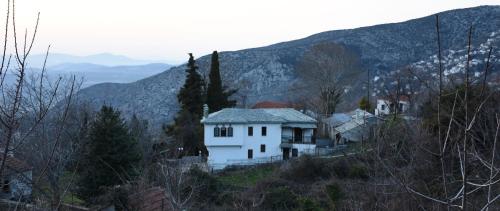 a white house on a hill with mountains in the background at Anna's Villa Portaria in Portariá