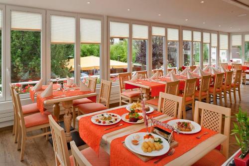 un restaurante con mesas y sillas rojas y ventanas en Hotel Park en Fiesch