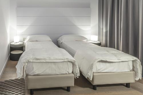 two beds in a room with white sheets at Tag Hotel in Fano