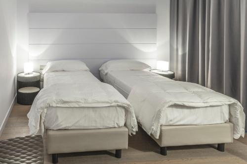 ファーノにあるTag Hotelのベッド2台(白いシーツ付)