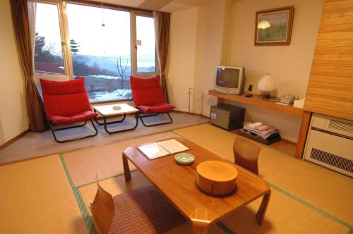 Una sala de estar con dos sillas rojas y una mesa. en Tazawa Kogen Hotel, en Senboku