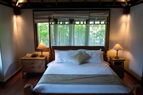 a bedroom with a bed with a window and two lamps at D'Sriwing Villa Gallery in Kuta