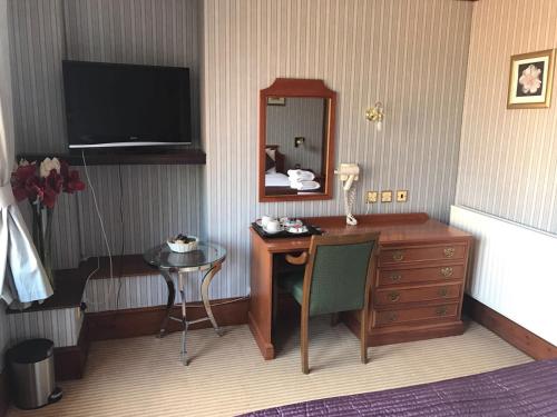 a room with a desk and a mirror and a table at Harefield Manor Hotel in Romford