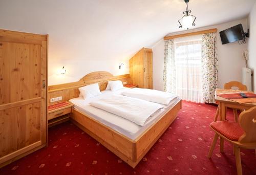 a bedroom with a large bed and a table at Pension Schrempfgut in Flachau
