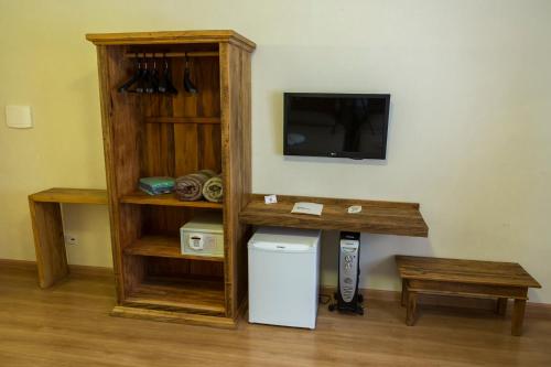 a room with a tv and a shelf with a refrigerator at Hotel Fazenda Santa Monica in Louveira