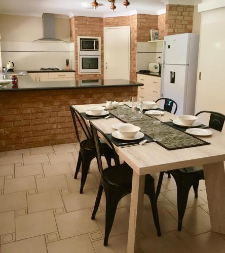 a kitchen with a wooden table with chairs and a kitchen with white appliances at Murdoch Station Bed & Breakfast in Perth