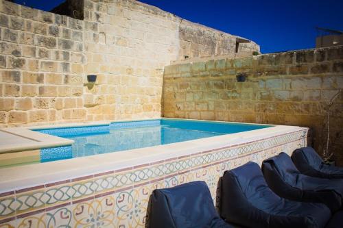 uma piscina com duas cadeiras em frente a uma parede de tijolos em Lemon Tree Relais by CX Collection em Żabbar