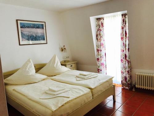 Un dormitorio con una cama con sábanas blancas y una ventana. en Hotel Ratskeller, en Zell an der Mosel