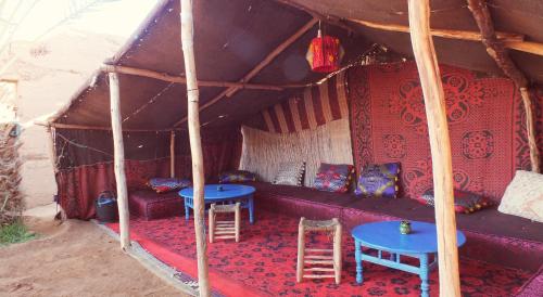 a room with a couch and tables in a tent at Auberge Tigida in Mhamid