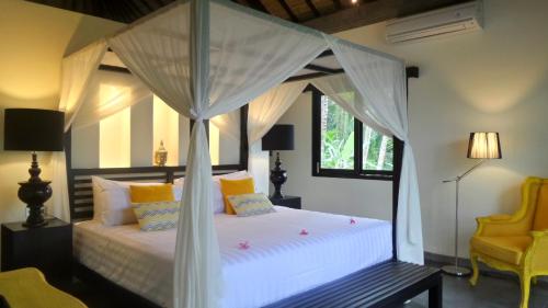 a bedroom with a white bed with a canopy at Rouge - Private Villa Condense in Ubud