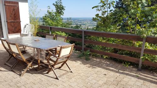 einen Holztisch und Stühle auf einer Terrasse in der Unterkunft La Villa du Chatelard in Ambierle