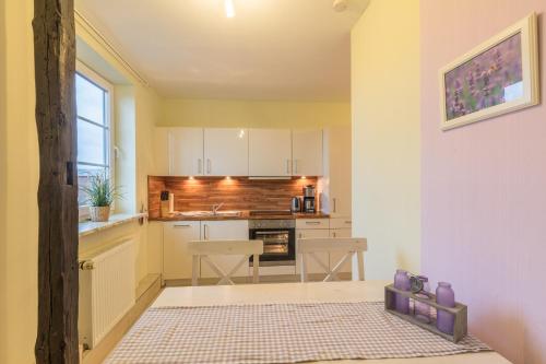 a small kitchen with white cabinets and a table at Bauernhof Marquardt in Fehmarn