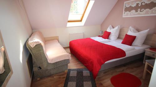 a small attic bedroom with a red bed and a chair at Blekitna Laguna Pobierowo in Pobierowo