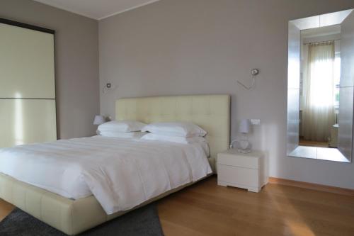 Un dormitorio blanco con una cama grande y un espejo. en Villa Brema, en Sirmione