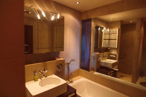 a bathroom with a sink and a tub and a mirror at Lindenhof Hotel Tepe in Damme