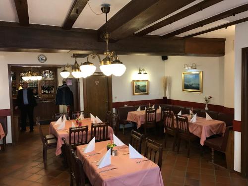 a restaurant with tables and chairs and a man in a suit at Hotel Ratskeller in Zell an der Mosel