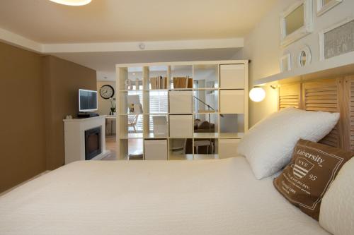 Schlafzimmer mit einem weißen Bett und einem TV in der Unterkunft Studio Sautille in Zandvoort