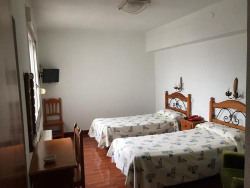 a hotel room with two beds and a table at Hostal Pancorbo in Pancorbo