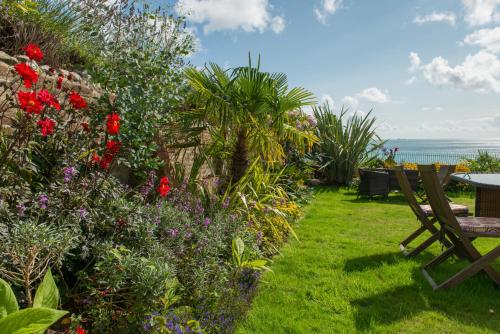 a garden with a bench and flowers and the ocean at The Clifton in Shanklin