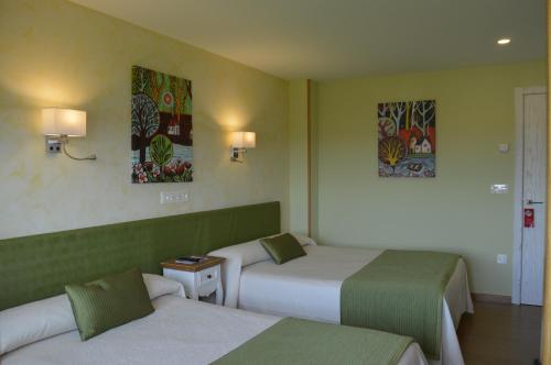 a hotel room with two beds and paintings on the wall at Hotel el Pinar in Villapedre