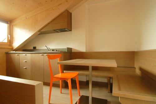 una pequeña cocina con mesa y silla naranja en Dolomiti Lodge Villa Gaia, en Valle di Cadore