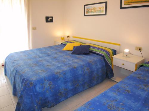1 dormitorio con 2 camas y edredón azul en Appartamenti Alaska en Bibione