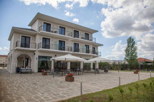 a large white building with tables and umbrellas at Filokalia Hotel in Ioannina