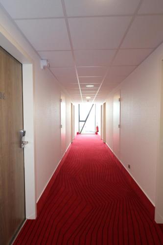 an empty corridor with red carpet in an office building at Hotel Arena Toulouse in Toulouse